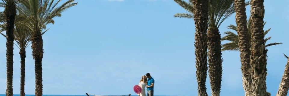 Couple enjoying themselves on the lawn during their holiday in Paphos for adults only at Pioneer Beach Hotel with the sea in the background.